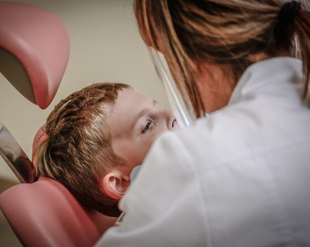 Young child receiving medical attention from a healthcare professional, likely in a clinical or intensive care setting.