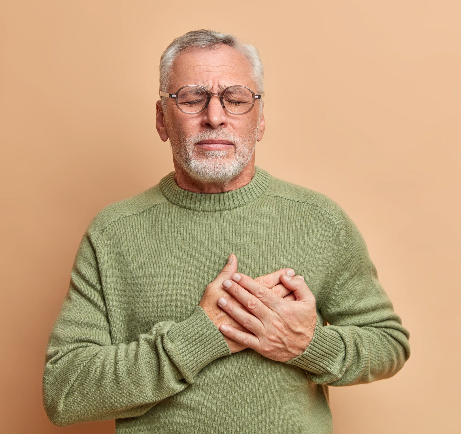 Senior man holding chest in pain, showing signs of heart attack or cardiac issue